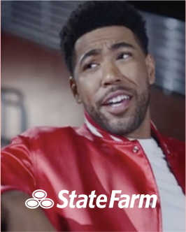 Closeup of Jake from StateFarm in a red satin jacket white a white StateFarm logo